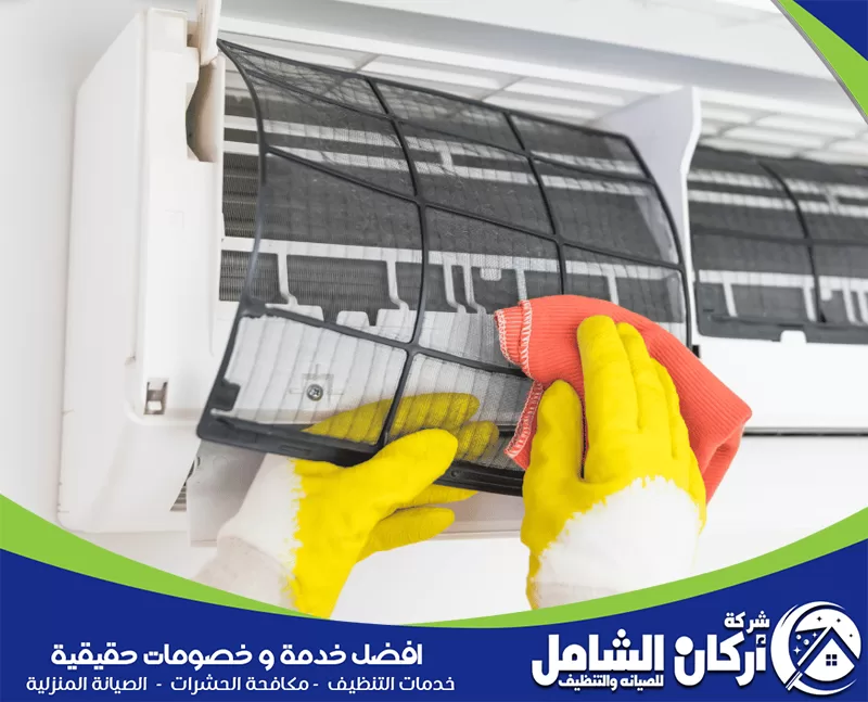 فني ينظف فلتر مكيف سبليت بقطعة قماش بعد إخراجه من الجهاز، في صورة توضح خطوة تنظيف الفلاتر لإزالة الغبار وتحسين كفاءة التبريد.