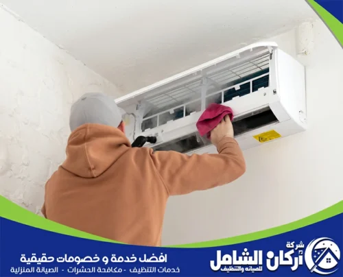 فني تنظيف مكيفات بتنظيف المكيف لضمان أداء مثالي وتبريد فعال. 
