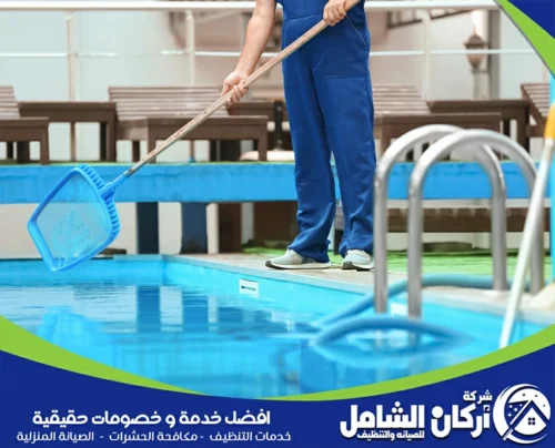 فني يستخدم شبكة تنظيف المسبح بالقطيف لإزالة الحطام من السطح، وبالجانب مكنسة المسبح لتنظيف القاع